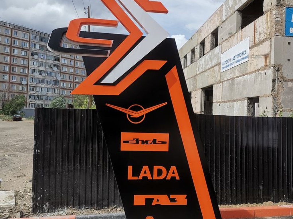 Totem publicitaire vertical noir et orange installé en extérieur